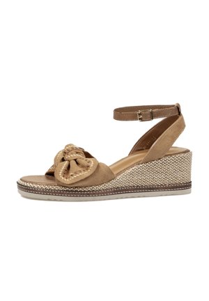 Sandalia beige de cuña con hebilla en la correa del tobillo, tacón de plataforma texturizado trenzado y gran lazo decorativo en la tira delantera.