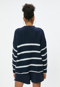 Navyblauer Strickpullover mit weißen horizontalen Streifen. Hat einen lockeren Schnitt, gerippte Bündchen und einen runden Halsausschnitt.