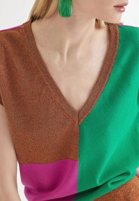 Wielokolorowy sweter z dekoltem w serek, z sekcjami w kolorze brązowym, zielonym i różowym. Dzianinowa faktura z delikatnym połyskiem.