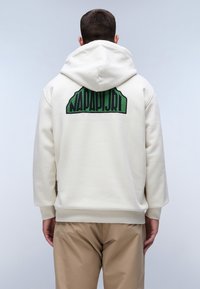 Felpa con cappuccio beige dalla texture morbida, con un logo ricamato verde sul retro. Maniche lunghe e cappuccio regolabile.