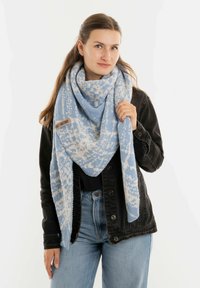 Sciarpa a maglia blu chiaro con un motivo geometrico, caratterizzata da una texture morbida e un'etichetta con logo. La sciarpa è drappeggiata in modo lasco attorno a chi la indossa.