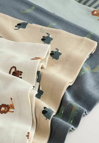 Quattro pezzi di tessuto con fantasie e stampe di animali giocosi. I colori includono crema, beige, grigio e azzurro pallido con texture morbide.