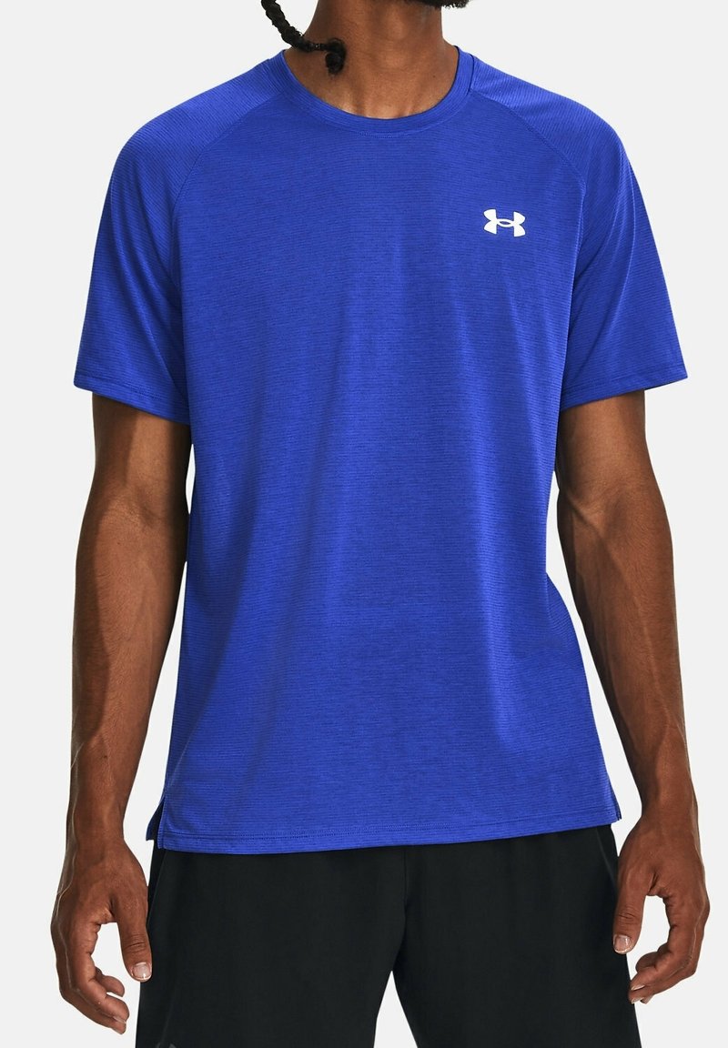 Modré sportovní tričko s krátkými rukávy, texturovanou látkou a kulatým výstřihem. Na levé horní straně hrudníku je bílá značka.