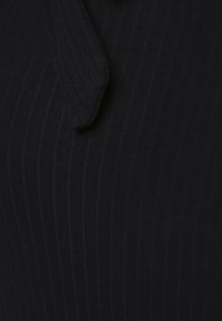 Tissu noir côtelé avec une couture courbée créant un pli subtil et surélevé dans le matériau.