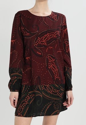 Abito a maniche lunghe in un profondo borgogna, con un motivo a paisley e pois in accenti neri e arancioni. Tessuto morbido, vestibilità rilassata, lunghezza sopra il ginocchio.