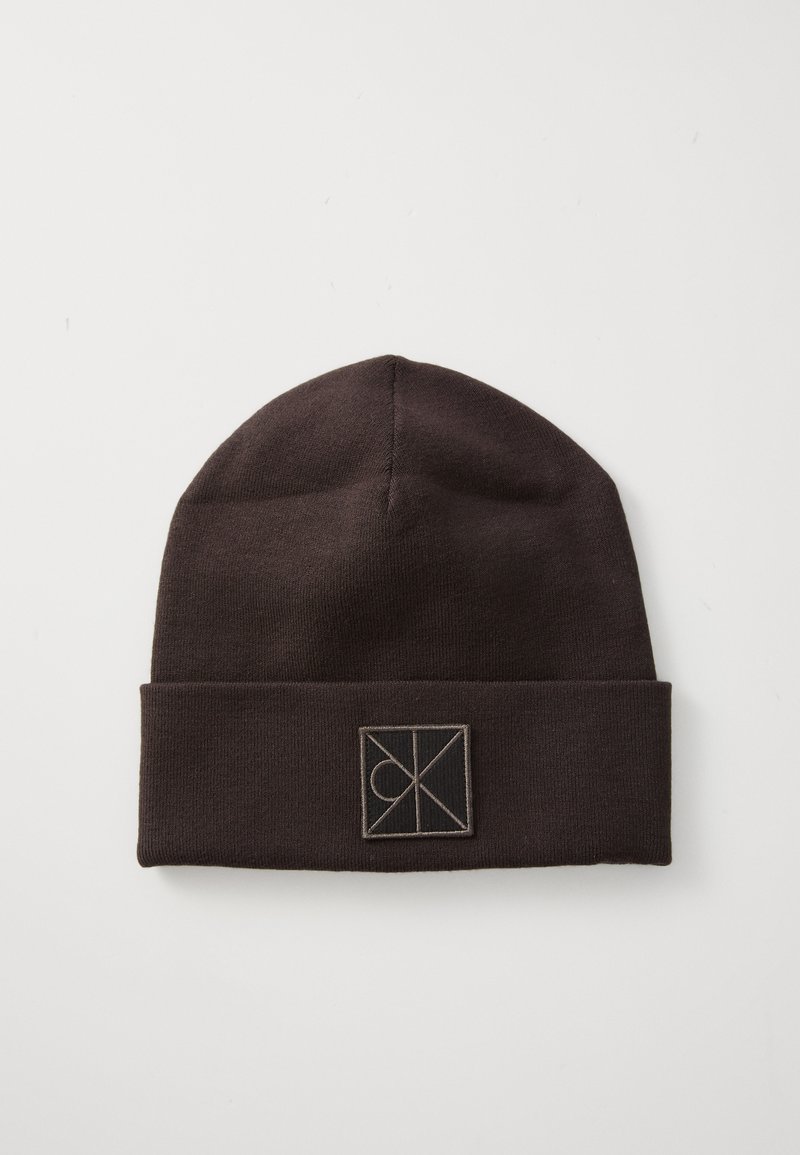 Beanie in maglia marrone con risvolto, caratterizzato da un piccolo logo quadrato di colore contrastante. Texture liscia e design a forma arrotondata.