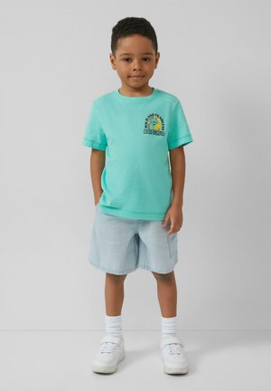 Turquoise katoenen t-shirt met een ronde hals en korte mouwen, met een kleurrafisch ontwerp. Gecombineerd met lichtblauwe shorts en witte sneakers.
