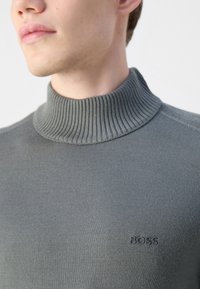 Harmaa ribattu poolopaita, jossa on istuva malli ja huomaamaton tuotemerkki samansävyisessä värissä rinnassa.
