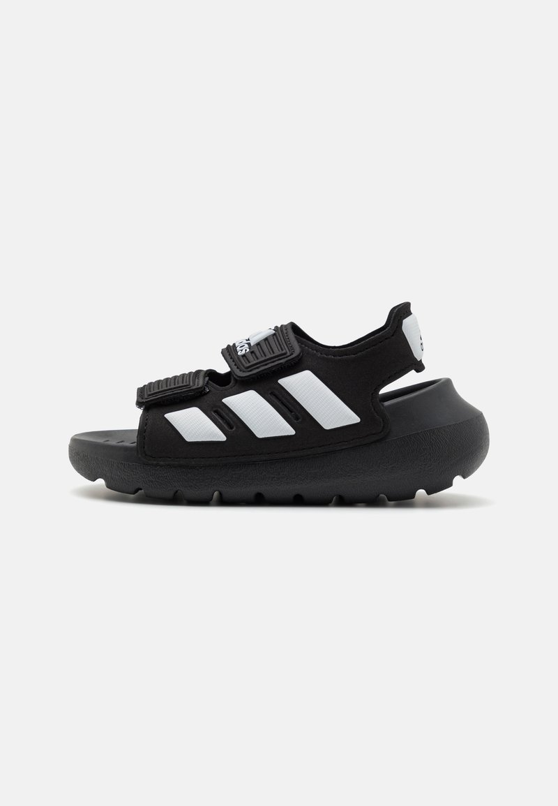 Black sandal with white accents, two adjustable straps, and a textured sole. Features a rounded toe and a chunky, cushioned outsole.