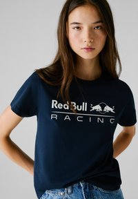 Maglietta in cotone blu navy con il logo "Red Bull Racing" in bianco accompagnato da due tori in carica, maniche corte e scollatura classica.