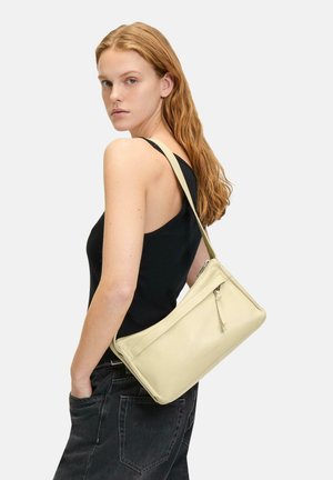 Sac à bandoulière en cuir beige de forme rectangulaire, avec une poche zippée à l'avant et une bandoulière fine. Texture lisse, design minimaliste.