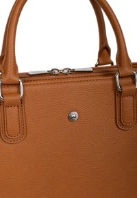 Bruine leren handtas met textuur, voorzien van dubbele bovenhandvatten, zilverkleurige hardware en een ritssluiting. Heeft een decoratieve logo-accent aan de voorkant.