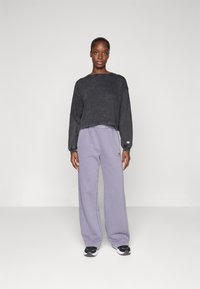 Black cropped sweatshirt with long sleeves, light purple wide-leg sweatpants, and black sneakers with white accents. Cotton material.