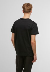 Black cotton t-shirt with a classic crew neck and short sleeves, featuring a solid texture and relaxed fit, viewed from the back.