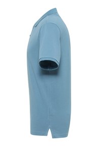 Błękitna koszulka polo, z krótkim rękawem, wykonana z materiału bawełnianego, z zapięciem na trzy guziki, klasycznym kołnierzykiem oraz prostym dołem z bocznymi wentylami.