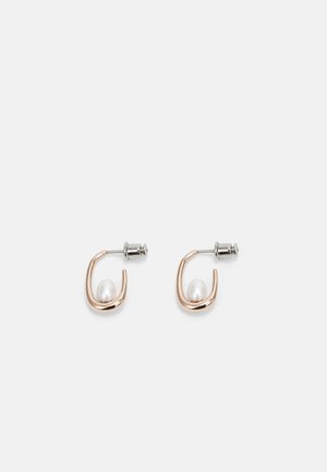 Petites boucles d’oreilles créoles en or, chacune ornée d’une perle blanche unique à l’intérieur et d’un fermoir papillon en argent.