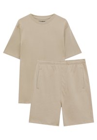 T-shirt beige à manches courtes avec col rond, associé à un short assorti à taille élastique, doté de poches latérales et d'une broderie de logo discrète.