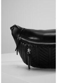 Sac en cuir noir avec dessus lisse et bas matelassé à motif chevron. Fermeture éclair avec détails en métal argenté. Forme arrondie.