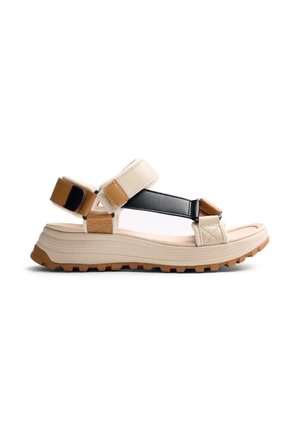 Sandalo sportivo beige e marrone con suola spessa, cinturini regolabili in Velcro e una fascia nera sopra per supporto.