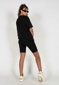 Black oversized t-shirt paired with black bike shorts, complemented by white sneakers. Smooth texture and casual design.