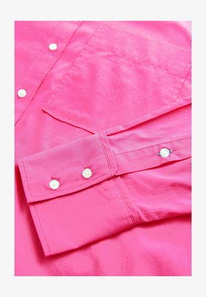 Kirkas roosa pikkidegadega pluus, millel on sile tekstuur, nupud ja rinna tasku. Sisaldab rullitud varrukaid koos nupudetailidega.