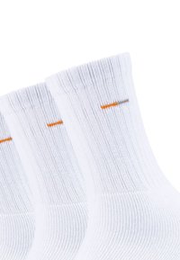 Weiße Baumwollsocken mit gerippter Textur, die einen orangen horizontalen Streifen nahe dem Bündchen aufweisen. Drei Paare sind zusammen gezeigt.