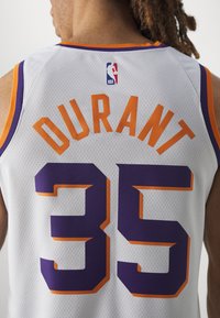 Maillot de basket en tissu en maille. Fond blanc avec des accents violets et orange. "DURANT" imprimé en orange ; grand numéro "35" en violet.