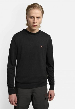 Maglione nero a maglia con scollatura a girocollo e polsini a costine. Presenta un piccolo dettaglio emblematico sul petto. Il tessuto appare liscio.