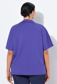 Lila Kurzarmoberteil mit klassischem Kragen, weichem Material und geradem Schnitt. Verfügt über eine einzelne Rückennaht für einen eleganten Look.