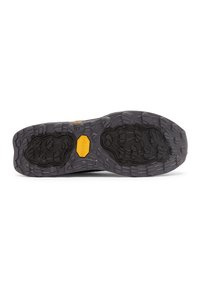 Zwarte rubberen schoenzool met een gestructureerd patroon en diepe profielen, met in het midden een geel Vibram-logo.