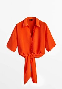 Blouse orange vif à manches courtes avec col et nœud à l'avant, présentée sur fond blanc.