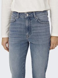 Vaaleansiniset farkut, joissa on istuva malli, viiden taskun tyyli ja keskikorkea vyötärö. Niissä on yksittäinen nappi ja vetoketjullinen etuläppä.