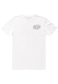 Camiseta de algodón blanca con mangas cortas y cuello redondo. Presenta un logo de escudo gris con "DEUS" en el pecho izquierdo. Diseño simple.