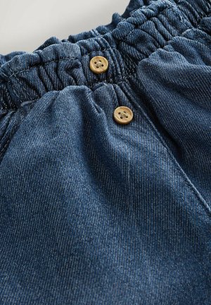 Džínové šortky s elastickým pásom, dvoma drevenými gombíkmi a jemným modrým prešívaním. Mäkká textúra a pohodlný strih.