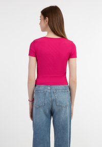 Top scurt cu maneci scurte, ajustat, din material ribbed de culoare roz aprins, combinat cu blugi largi de culoare albastru deschis, având un design clasic cu cinci buzunare.