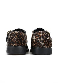 Buty w wzór panterki z miękką teksturą futra, czarnymi skórzanymi akcentami, płaską czarną podeszwą oraz złotym zapięciem po boku.
