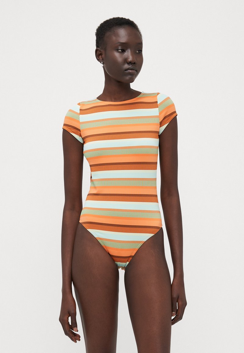 Maillot de bain une pièce rayé avec des couleurs orange, vert menthe et marron. Manches courtes, ouvertures de jambe hautes et texture côtelée.