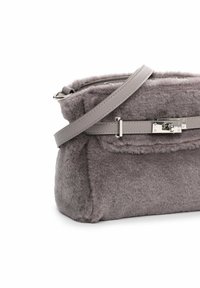 Harja faux fur -laukku, jossa on suorakulmainen muoto, nahkaremmi ja hopeiset yksityiskohdat. Varustettu läppäkiinnityksellä ja kiillotetulla lukolla.