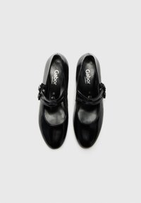 Chaussures Mary Jane en cuir noir avec une finition brillante, présentant une seule sangle, une boucle ajustable et un design à bout arrondi. Logo Gabor visible.