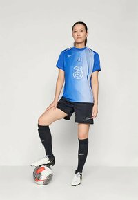 Maillot d'équipe bleu et blanc avec des rayures diagonales, shorts noirs, chaussettes de soccer noires et chaussures blanches. Présente un logo et le numéro "3".