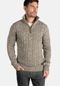 Brun kabelstrikket sweater med høj krave og lynlås, udstyret med ribbede manchetter og et struktureret mønster. Stoffet virker varmt og hyggeligt.