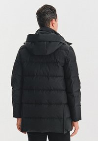 Czarna kurtka puchowa z poziomymi szwami, kapturem i długimi rękawami. Materiał wydaje się gładki i ma matowe wykończenie.