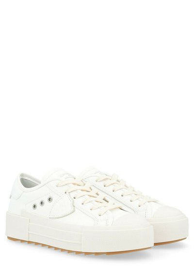 Sneakers bianchi in canvas con suola in gomma, caratterizzati da un profilo basso, punta tonda e tre occhielli rinforzati di lato. Dettagli in gomma testurizzata.