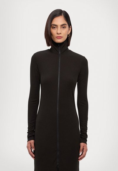 Robe longue noire en tissu doux avec un col haut et une fermeture éclair sur toute la longueur, dotée de manches longues ajustées et d'une silhouette épurée.