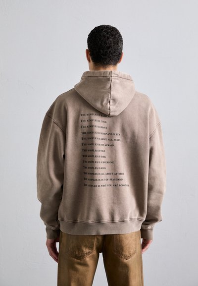 Braunen Hoodie mit einer Kordelzugkapuze, der auf der Rückseite wiederholt in Schwarz bedruckt ist. Hergestellt aus weichem Stoff, mit einem lässigen Schnitt und gerippten Bündchen.