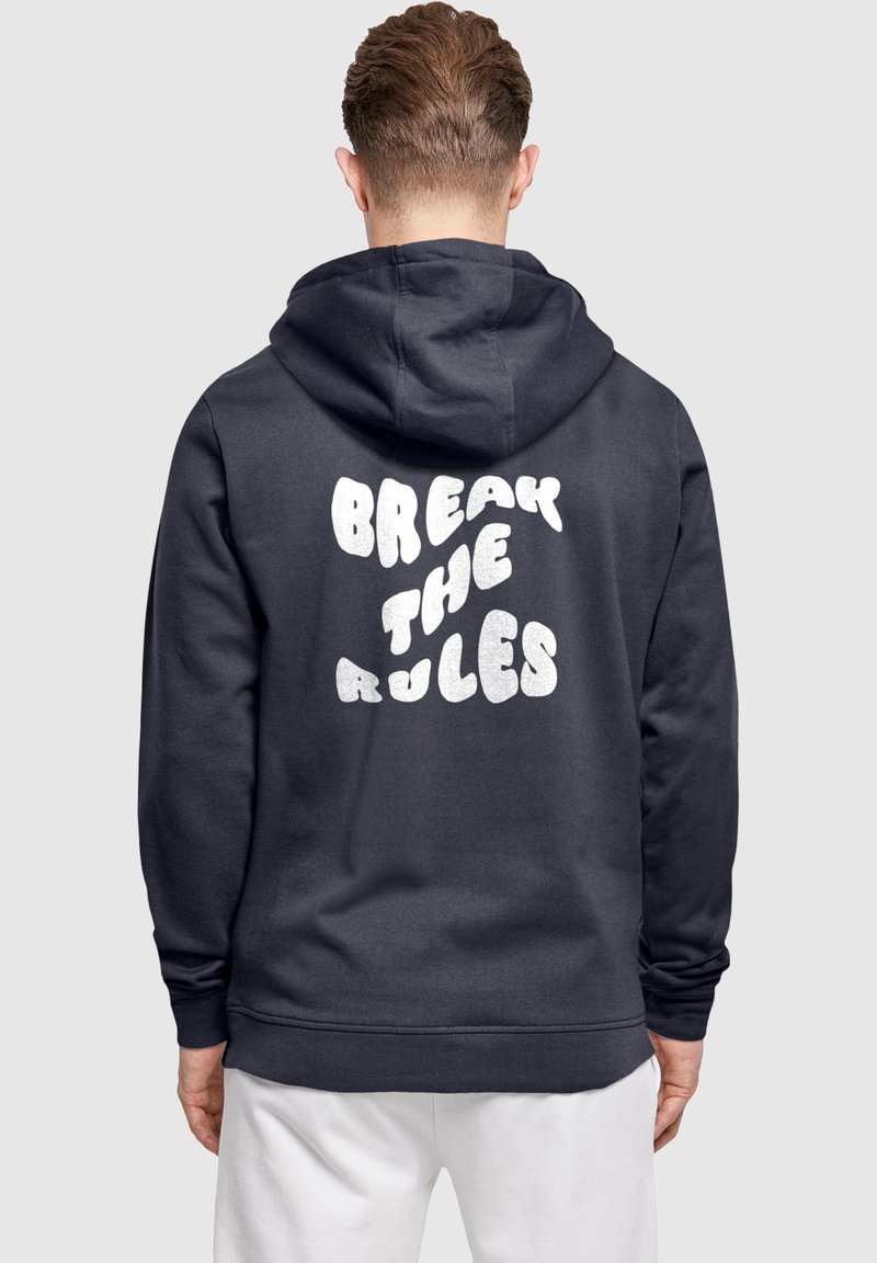 Marineblauer Hoodie mit einem großen, flauschigen weißen Schriftzug auf dem Rücken, der "BREAK THE RULES" lautet; mit einer Kapuze mit Kordelzug und gerippten Bündchen.