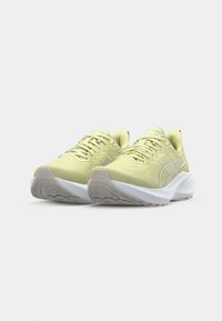 Baskets de sport jaunes clair avec un tissu texturé, une semelle intermédiaire blanche et une semelle en caoutchouc. Design à lacets avec des accents de marque sur le côté.