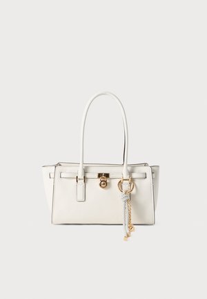 Witte leren handtas met twee lange handvatten, gouden hardware, rechthoekige vorm, met een charme met een ketting en knoopdetails.