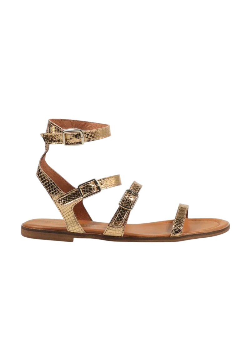 Sandalia plana de piel de serpiente dorada con múltiples correas ajustables y herrajes metálicos. Planta de cuero marrón y un ligero tacón.
