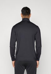 Schwarzer Langarmpullover mit hohem Kragen, aus glattem, elastischem Stoff hergestellt. Verfügt über taillierte Ärmel und einen flachen Saum in der Taille.